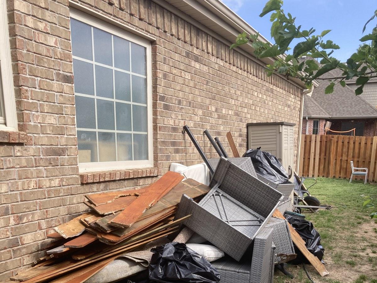 Outdoor furniture and debris pile against a house ready for pickup